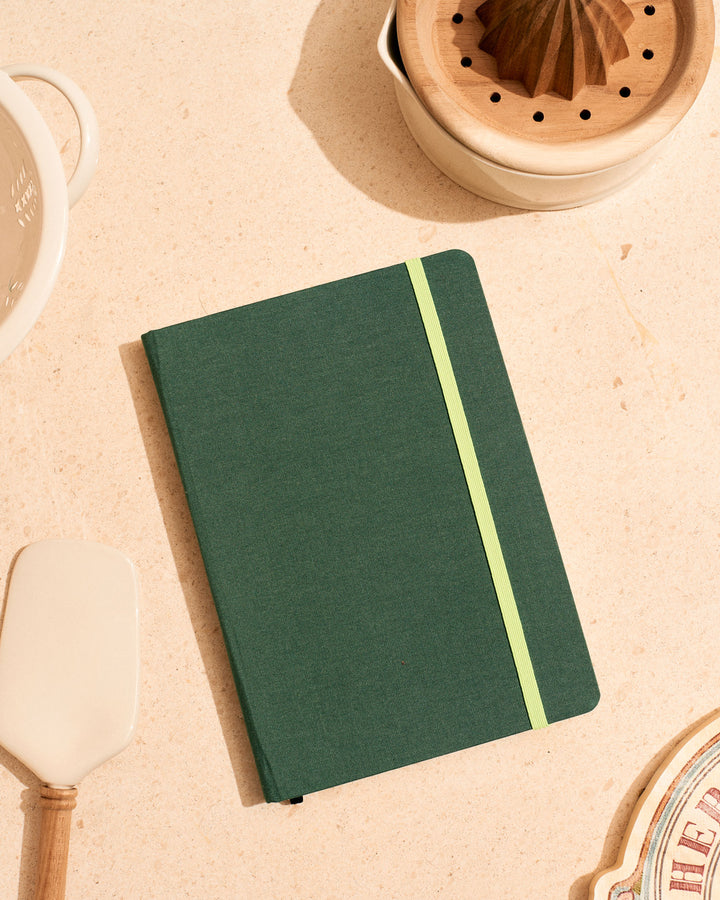 Cuaderno de tela verde con goma de cierre fluor